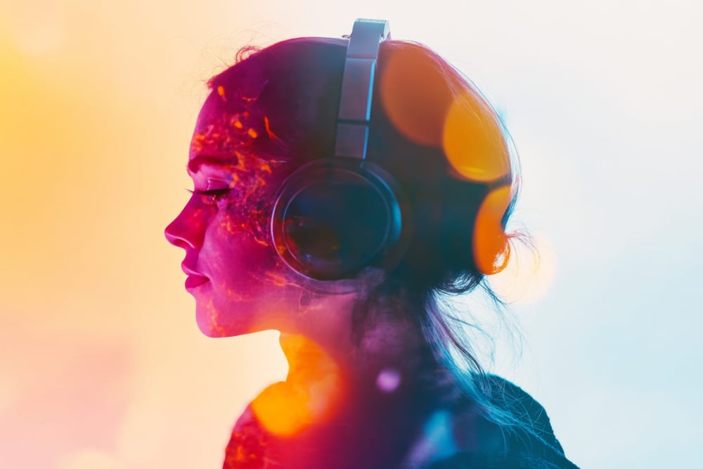 Psychedelic photograph of a woman wearing headphones and listening to music with a contemplative look on her face.