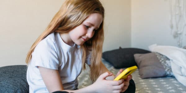 Photo of a young girl fully absorbed in her bright yellow phone.