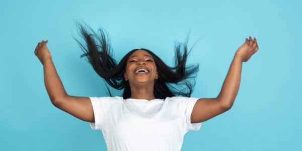 Photo of a stress-free African woman with her hands and her hair in the air.