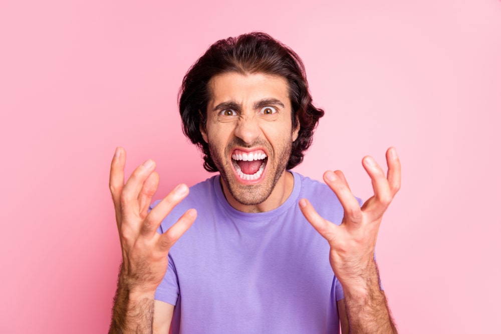 Photo of a stressed-out man in a purple shirt on a pink background.