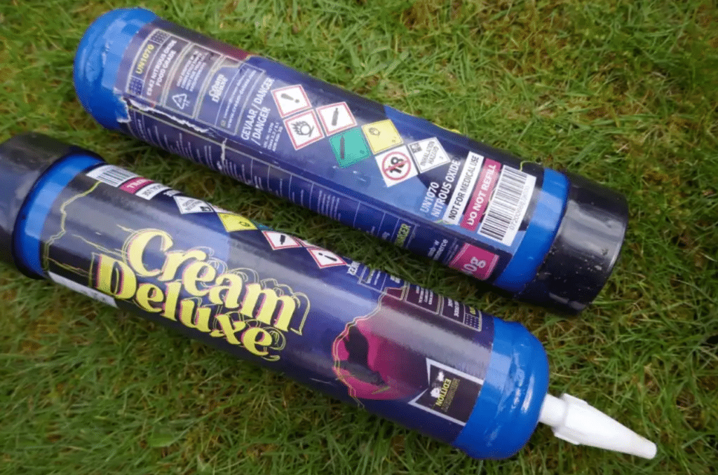 Photo of two nitrous oxide canisters laying in the grass.