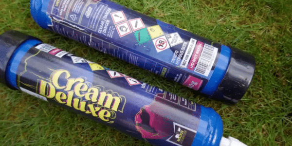 Photo of two nitrous oxide canisters laying in the grass.