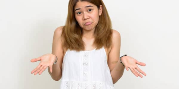 Photo of a young woman holding her hands palms up as if to indicate indecision or six-seven.