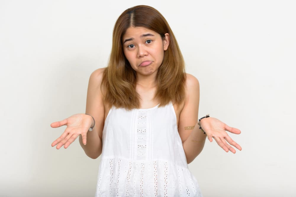 Photo of a young woman holding her hands palms up as if to indicate indecision or six-seven.