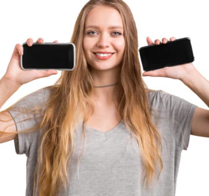 Photo of a young woman holding up two smartphones.