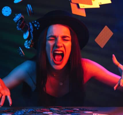 Photo of angry woman throwing poker chips and playing cards into the air in what looks like a dimly lit casino.