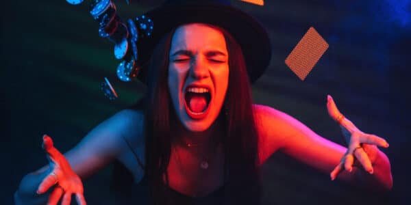 Photo of angry woman throwing poker chips and playing cards into the air in what looks like a dimly lit casino.