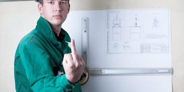 Photo of an engineer at a drafting board showing the middle finger to the camera.