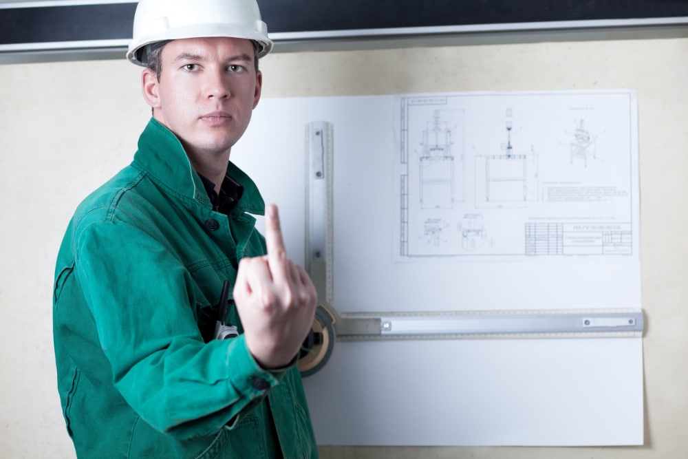 Photo of an engineer at a drafting board showing the middle finger to the camera.