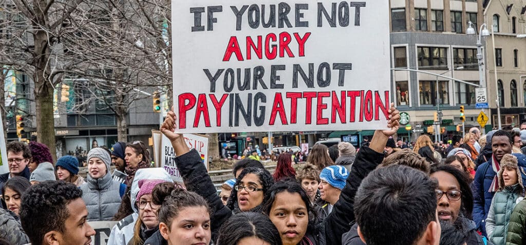Photograph of protesters holding signs and marching.