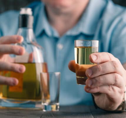 Photo of a man offering a drink of whiskey.