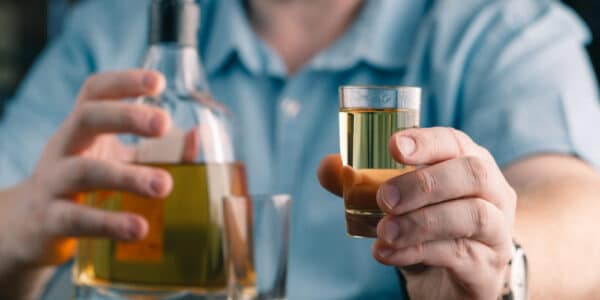 Photo of a man offering a drink of whiskey.