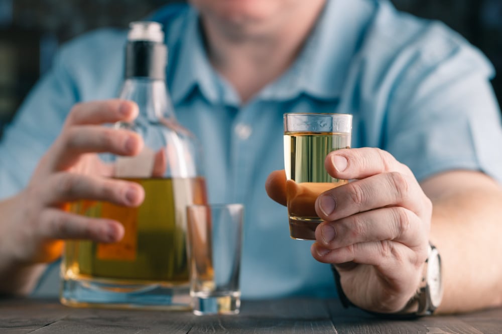 Photo of a man offering a drink of whiskey.