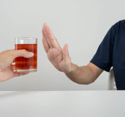 Photo of a man refusing a drink by holding up his hand against it.