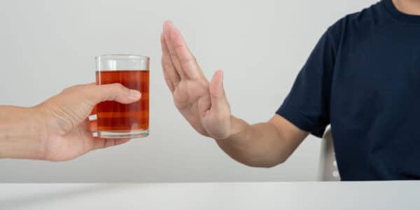 Photo of a man refusing a drink by holding up his hand against it.