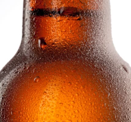 Close up photo of beer bottle with water drops and frost isolated on white.