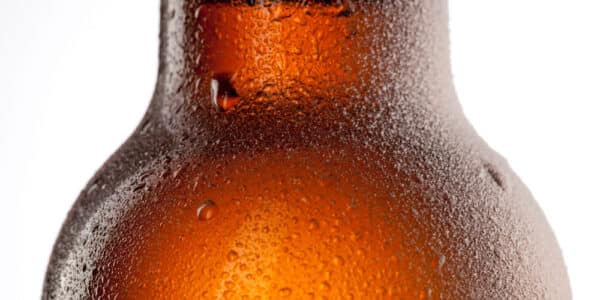 Close up photo of beer bottle with water drops and frost isolated on white.