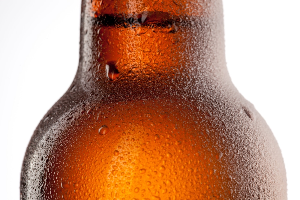 Close up photo of beer bottle with water drops and frost isolated on white.