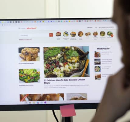 Photo of a man looking at a computer screen filled with images of delicious foods.