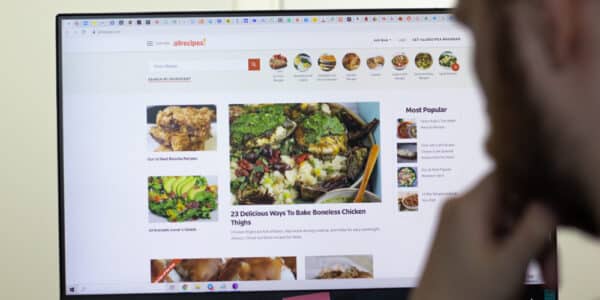 Photo of a man looking at a computer screen filled with images of delicious foods.