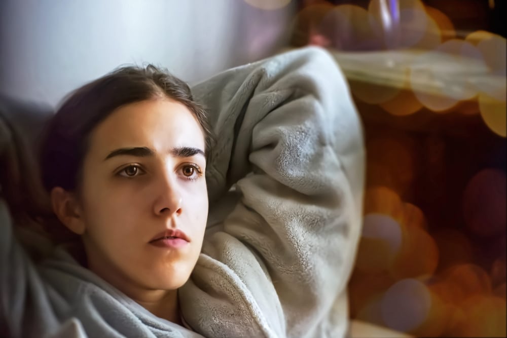 Photography of a young woman laying in bed unable to sleep due to stressful thoughts.