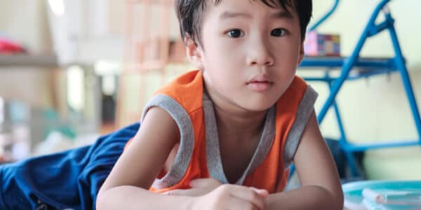 Young Asian child laying on the floor playing with a smartphone.