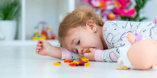 Baby laying on the floor eating gummy bears.