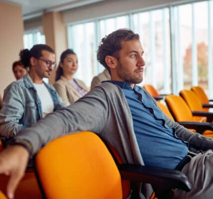 Photo of adults watching an addiction treatment video in a conference room.