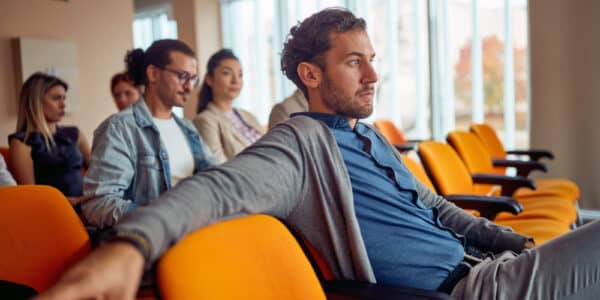 Photo of adults watching an addiction treatment video in a conference room.