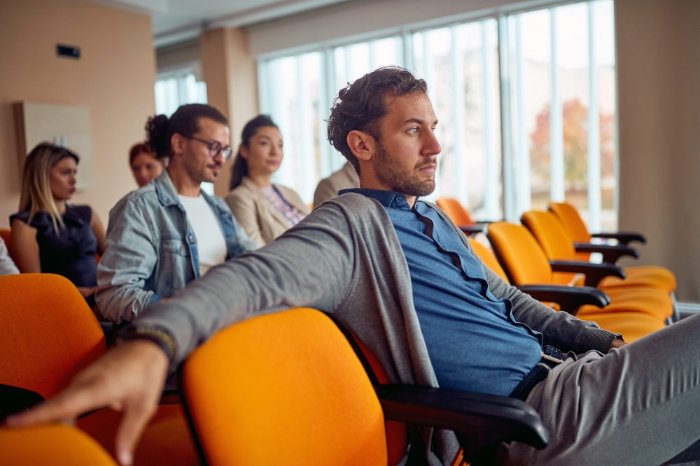Photo of adults watching an addiction treatment video in a conference room.