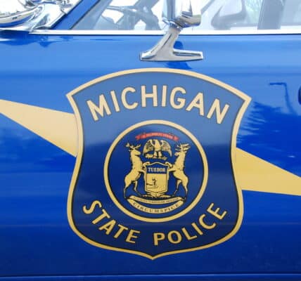 Photo of the side of a Michigan State Police cruiser showing the blue and yellow shield of the state police.