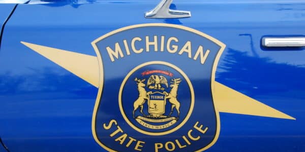 Photo of the side of a Michigan State Police cruiser showing the blue and yellow shield of the state police.