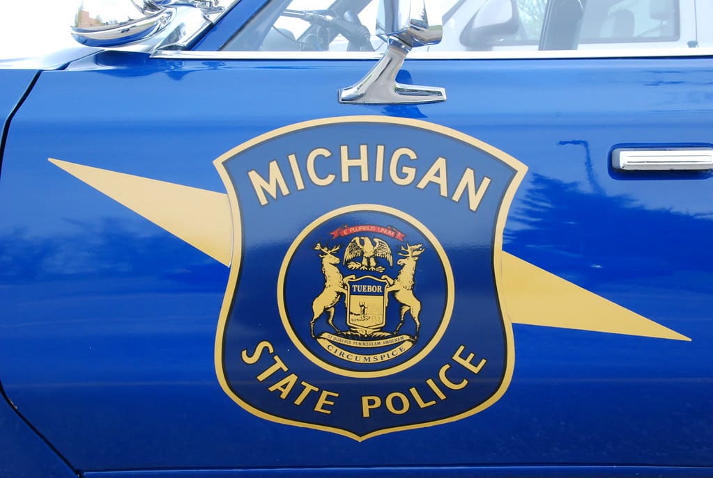 Photo of the side of a Michigan State Police cruiser showing the blue and yellow shield of the state police.