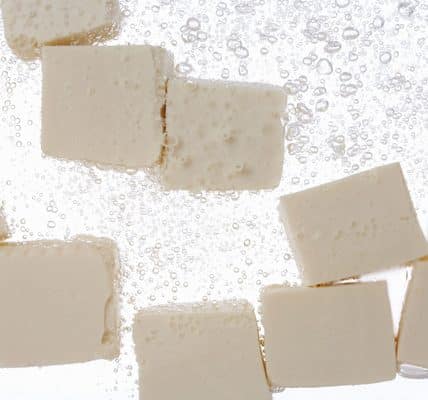 Tofu pieces submereged in water.