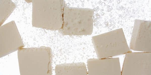 Tofu pieces submereged in water.