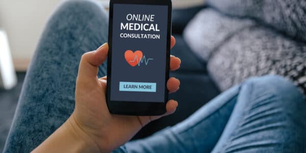 Photo of a person holding a smartphone that shows a screen offering an "Online Medical Consultation."