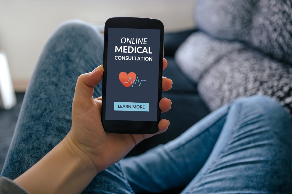 Photo of a person holding a smartphone that shows a screen offering an "Online Medical Consultation."