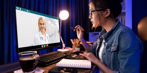 Photo of a young woman attending a weight loss coaching program through her computer.