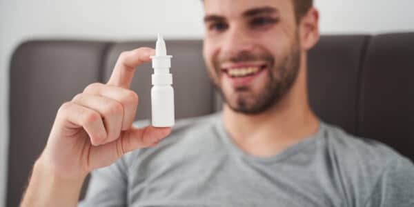 Photo of a young man looking fondly at a ketamine nasal spray injector.