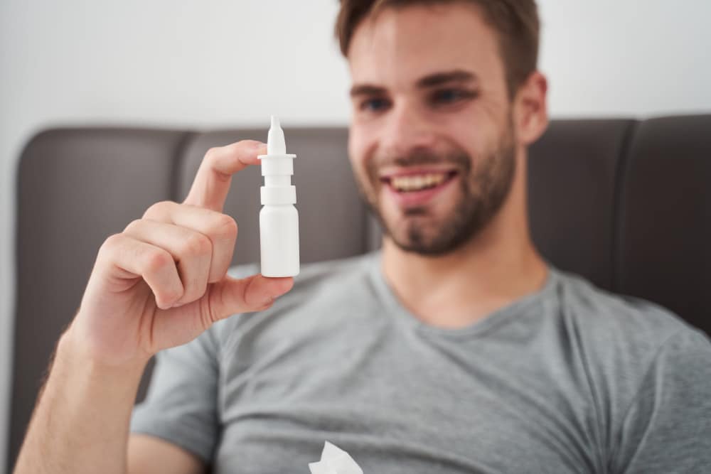 Photo of a young man looking fondly at a ketamine nasal spray injector.