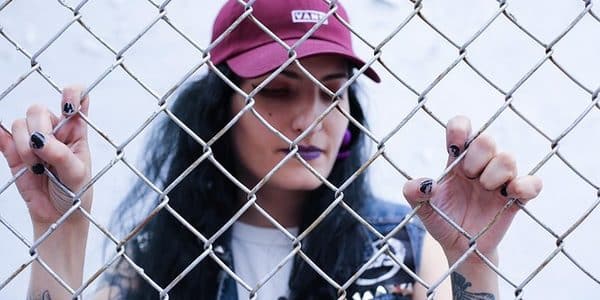 Image of a young woman standing behind a wire fence.